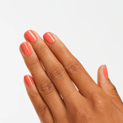Hand with coral-pink nail polish on a light gray background