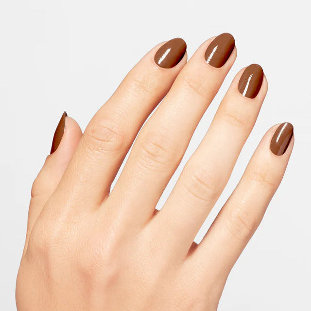 Hand with brown nail polish on a light gray background